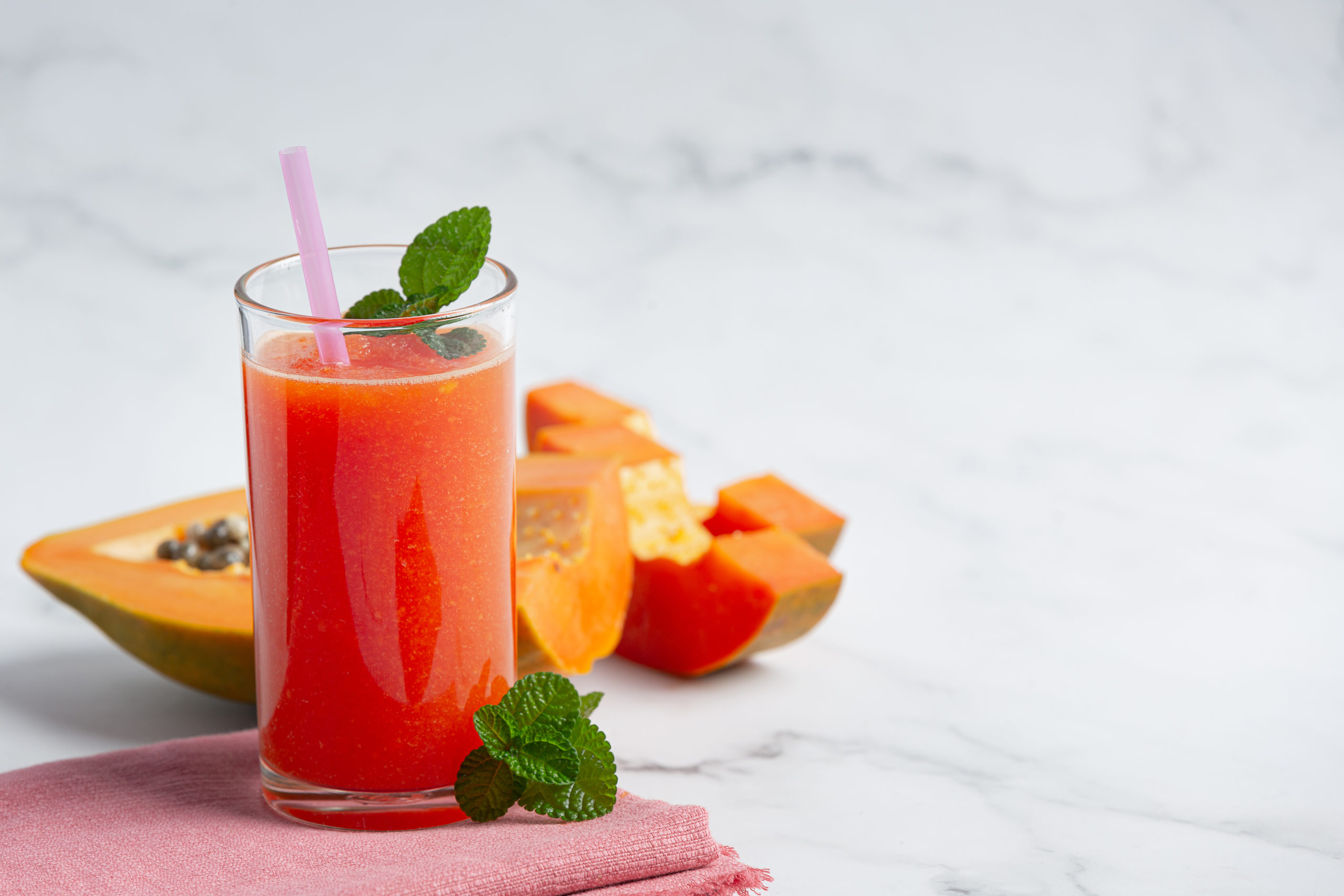 a glass of papaya juice put on white marble floor