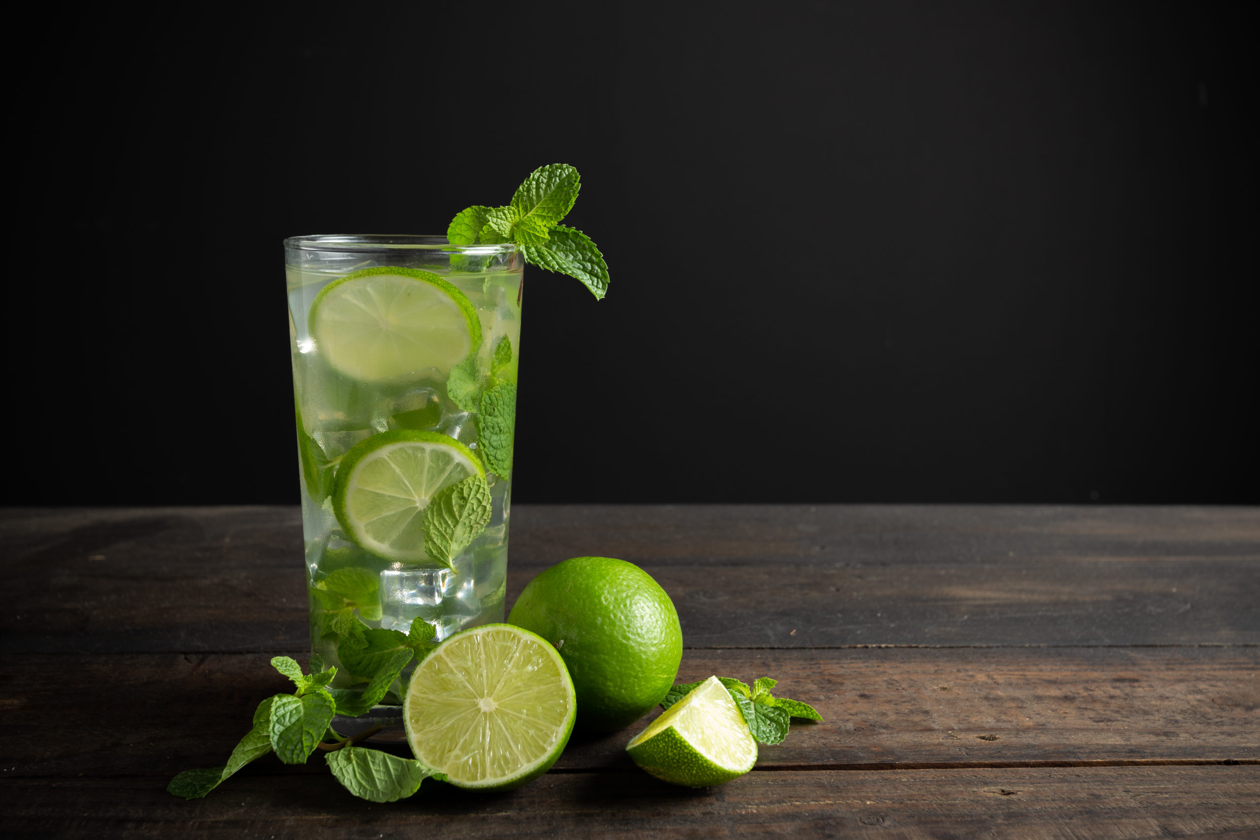Mojito drink with lime, lemon and mint on wooden table.